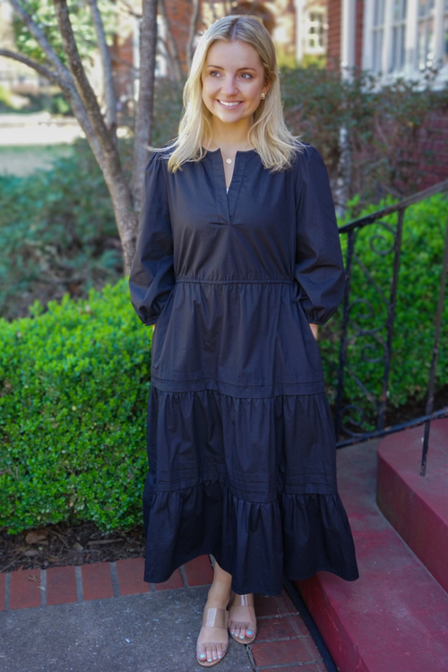 Model is wearing a black poplin midi dress with adjustable tie waist, 3/4" sleeves and v-neck design.