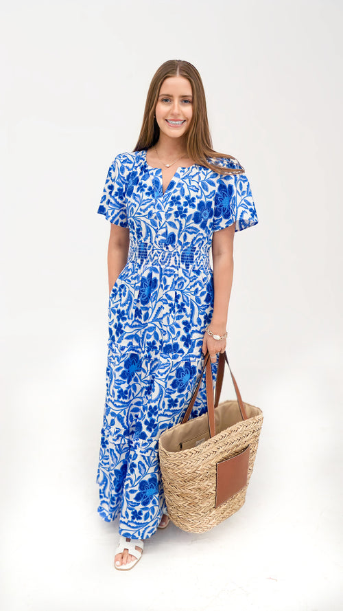 Model is wearing a blue and white maxi dress with bell sleeves and v-neck.