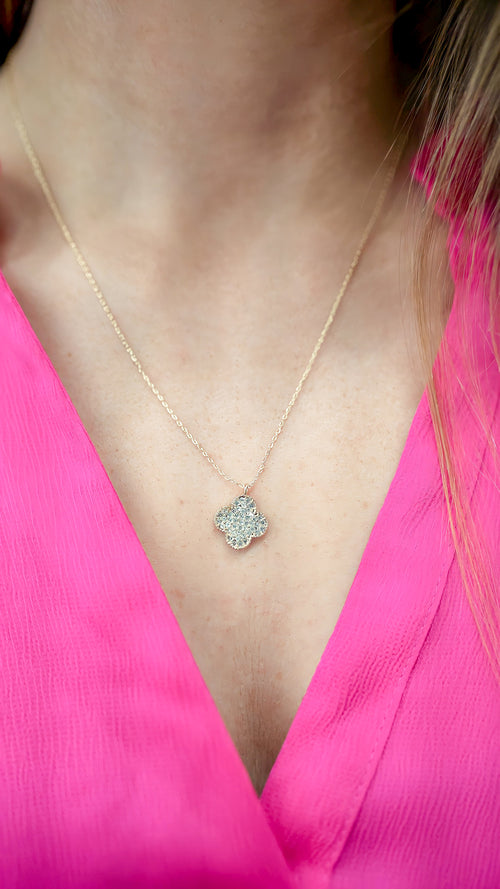 Model is wearing a gold thin chained necklace with dainty pave CZ quatrefoil deign.