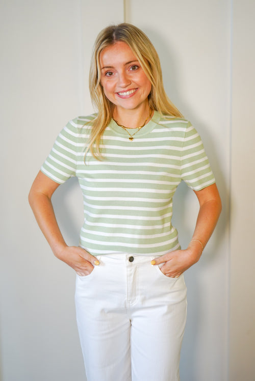 Model is wearing a light green and white striped t-shirt style knit top