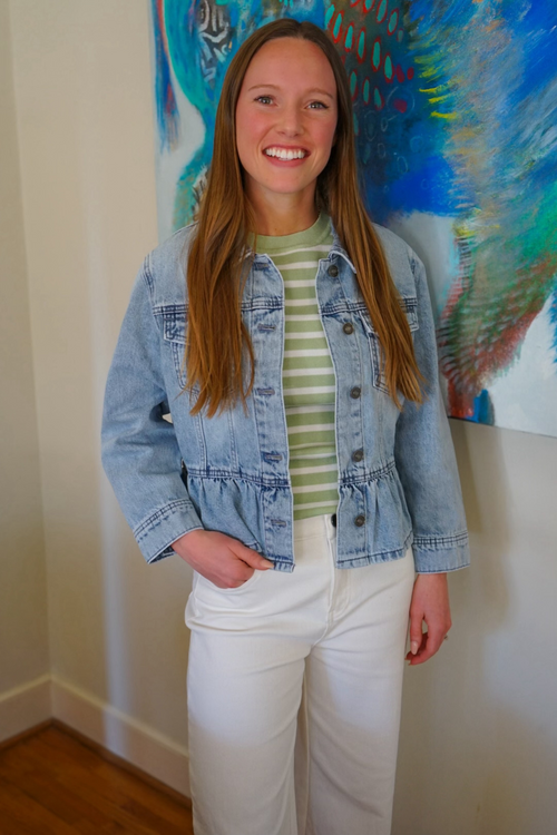 Model is wearing a light denim jean jacket with peplum detail at the waist