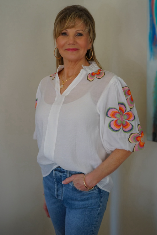 Model is wearing a THML white cotton top with colorful puff sleeves with flower embroidery