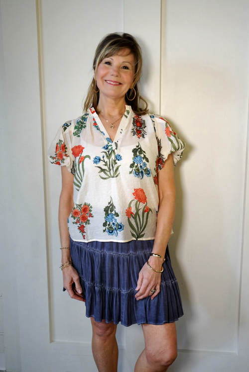 Model is wearing a THML short, puff sleeve blouse with blue, green and tomato red floral pattern