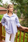 Model is wearing a classic light blue poplin shirt with pearl button detail and 3/4" sleeves that can be worn untucked