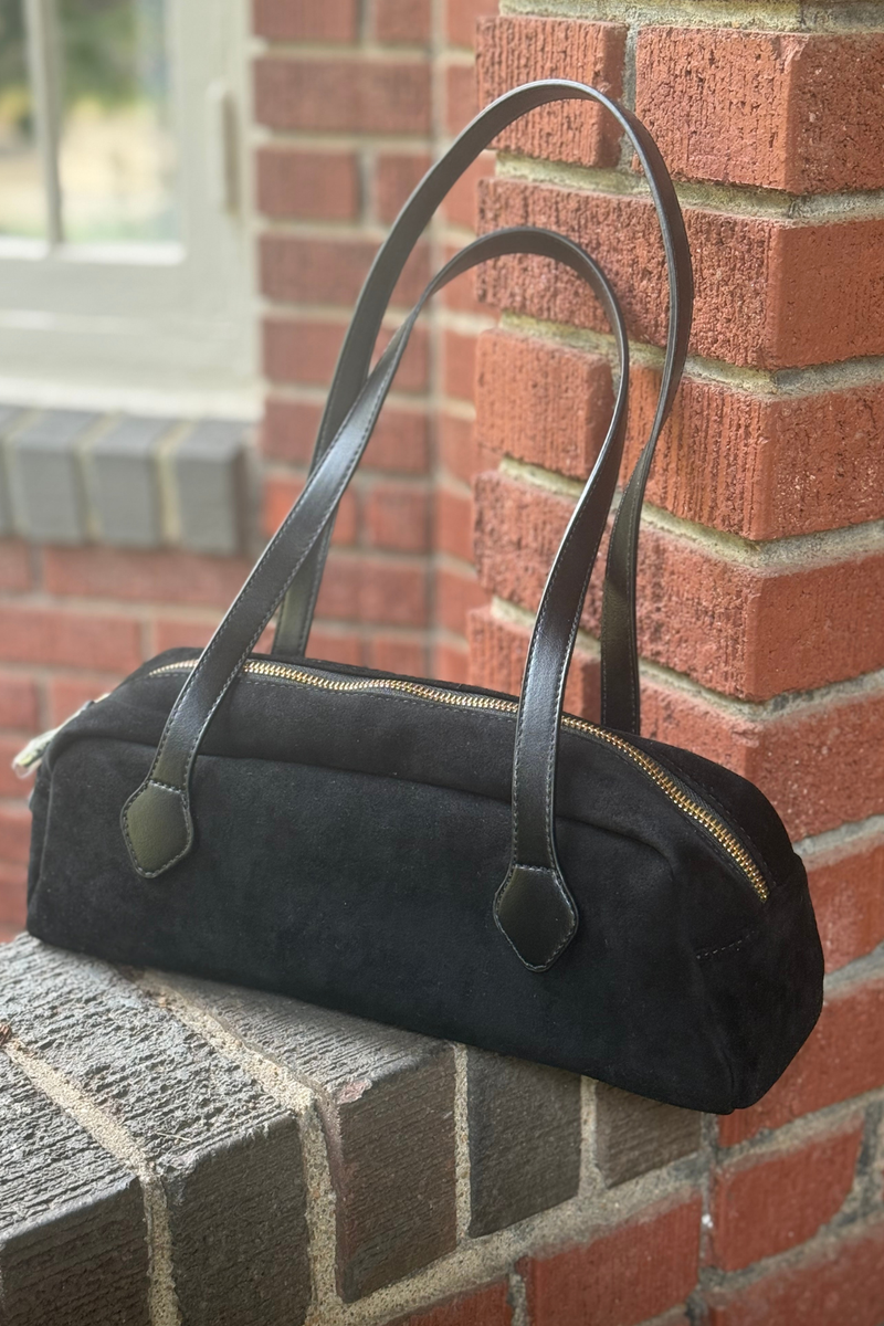 photo is showing a black faux leather nubuck east-west bag with gold hardware and shoulder strap.