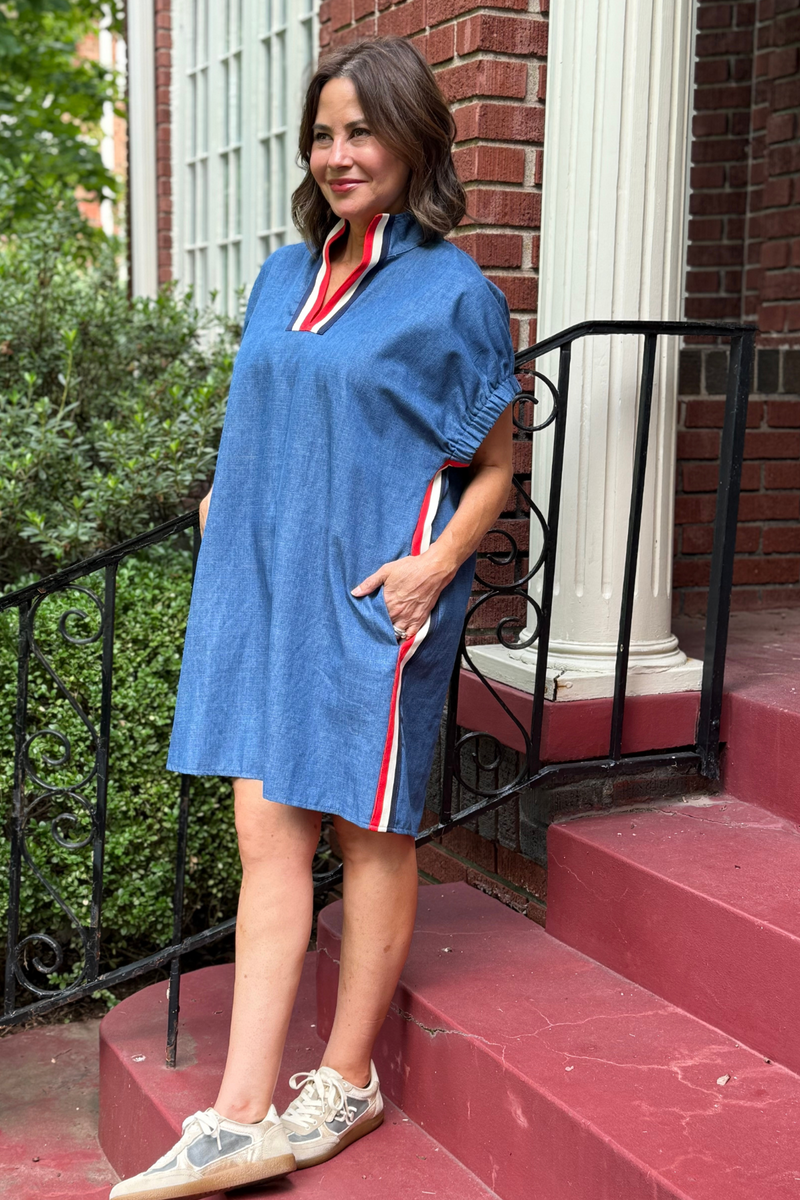Model is wearing a denim dress with white, navy and red tape down the side.