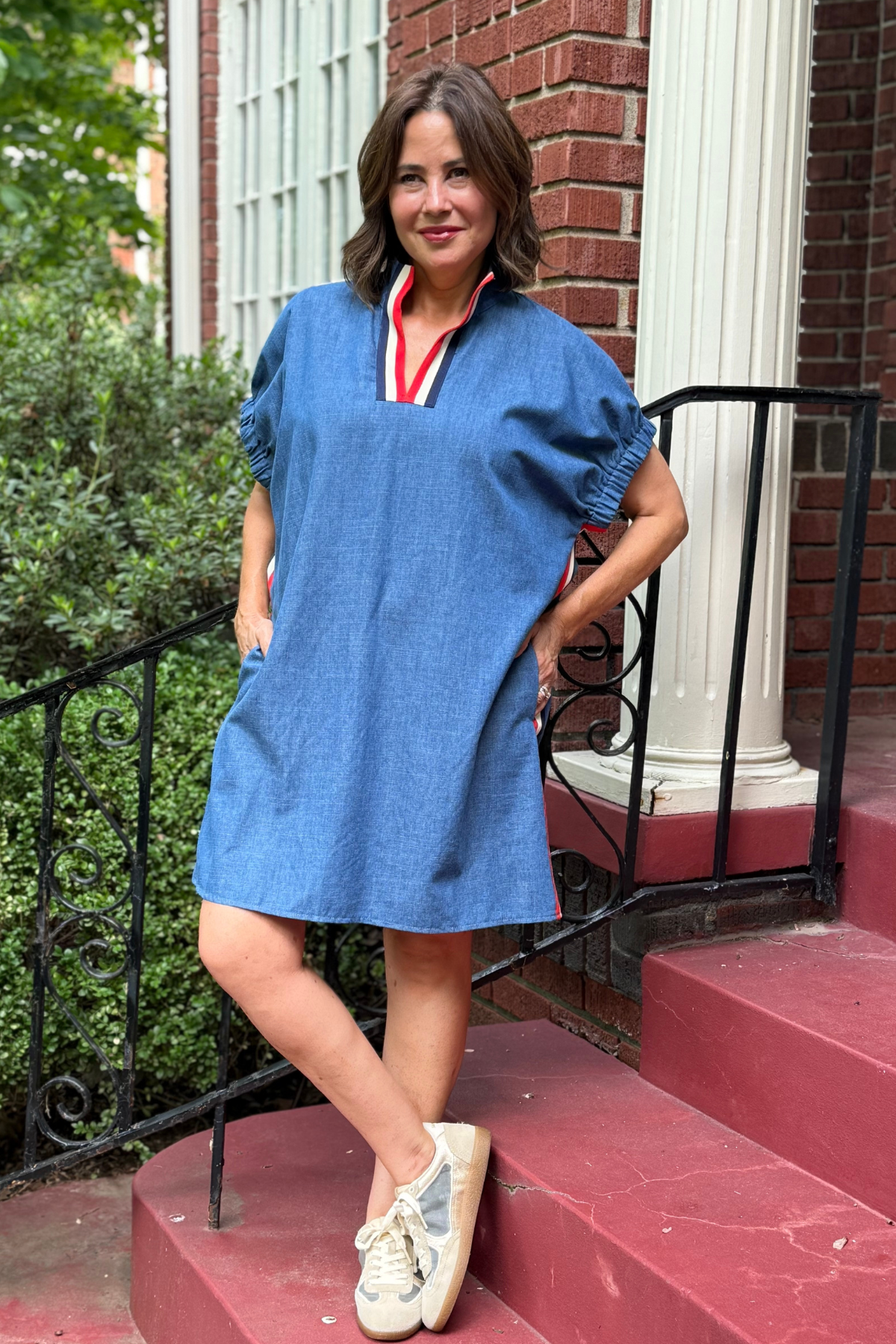 Model is wearing a blue dress with red , navy and white tape detail down the side.