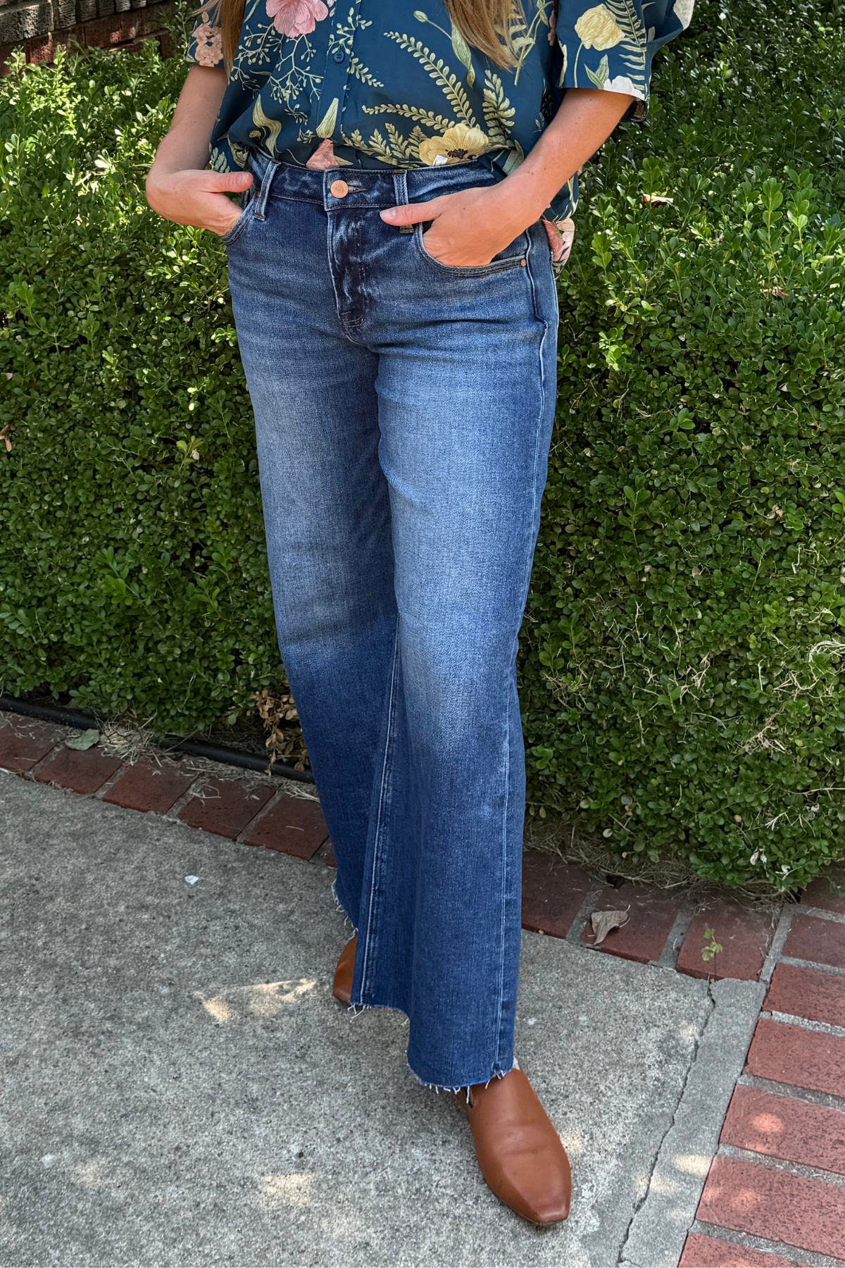 Model is wearing a full leg medium wash jean by Risen.
