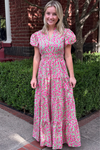 Model is wearing a pink and green ditsy print maxi dress with ruched waist, puff sleeves and a tiered skirt.