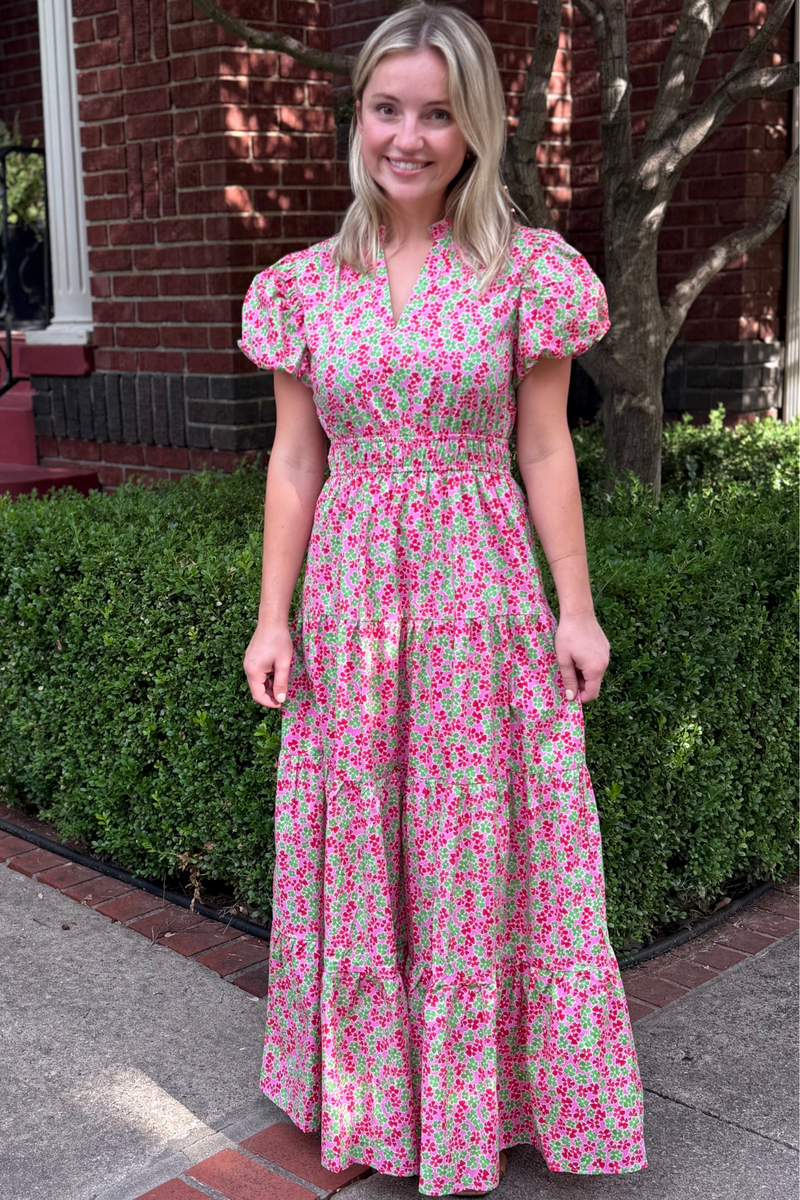 Model is wearing a pink and green ditsy print maxi dress with ruched waist, puff sleeves and a tiered skirt.