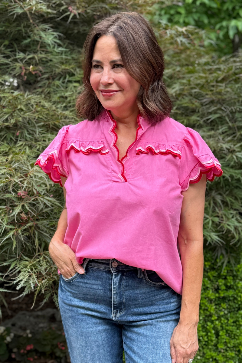 Model is wearing a hot pink top with pink and red piping along the neckline and sleeves.