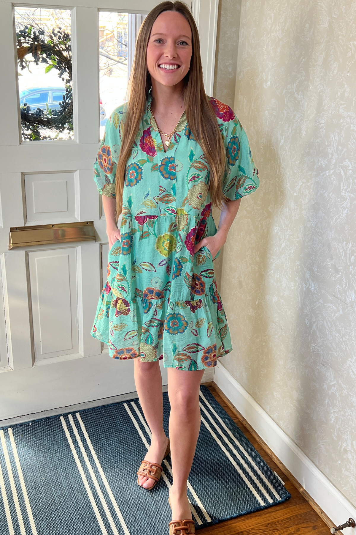 Model is wearing a green floral THML dress with v-neck, puff sleeves and ruffle skirt.