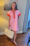 Model is wearing a pink THML dress with orange trim.