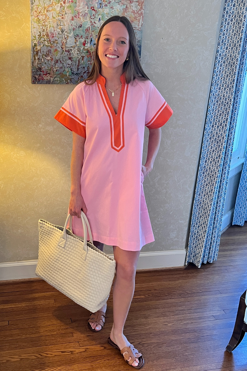 Model is wearing a pink THML dress with orange trim.