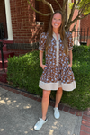 Model is wearing a chocolate, blue and cream floral dress with blue and cream ticking detail along the hem, sleeves, collar and placket.