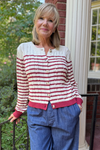 Model is wearing a lightweight cream cable knit cardigan with burgundy stripe detailing.