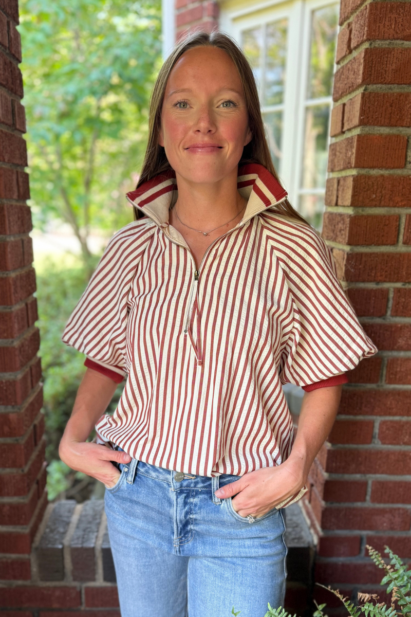 Model is wearing a crimson and cream seer sucker striped top with zipper collar.