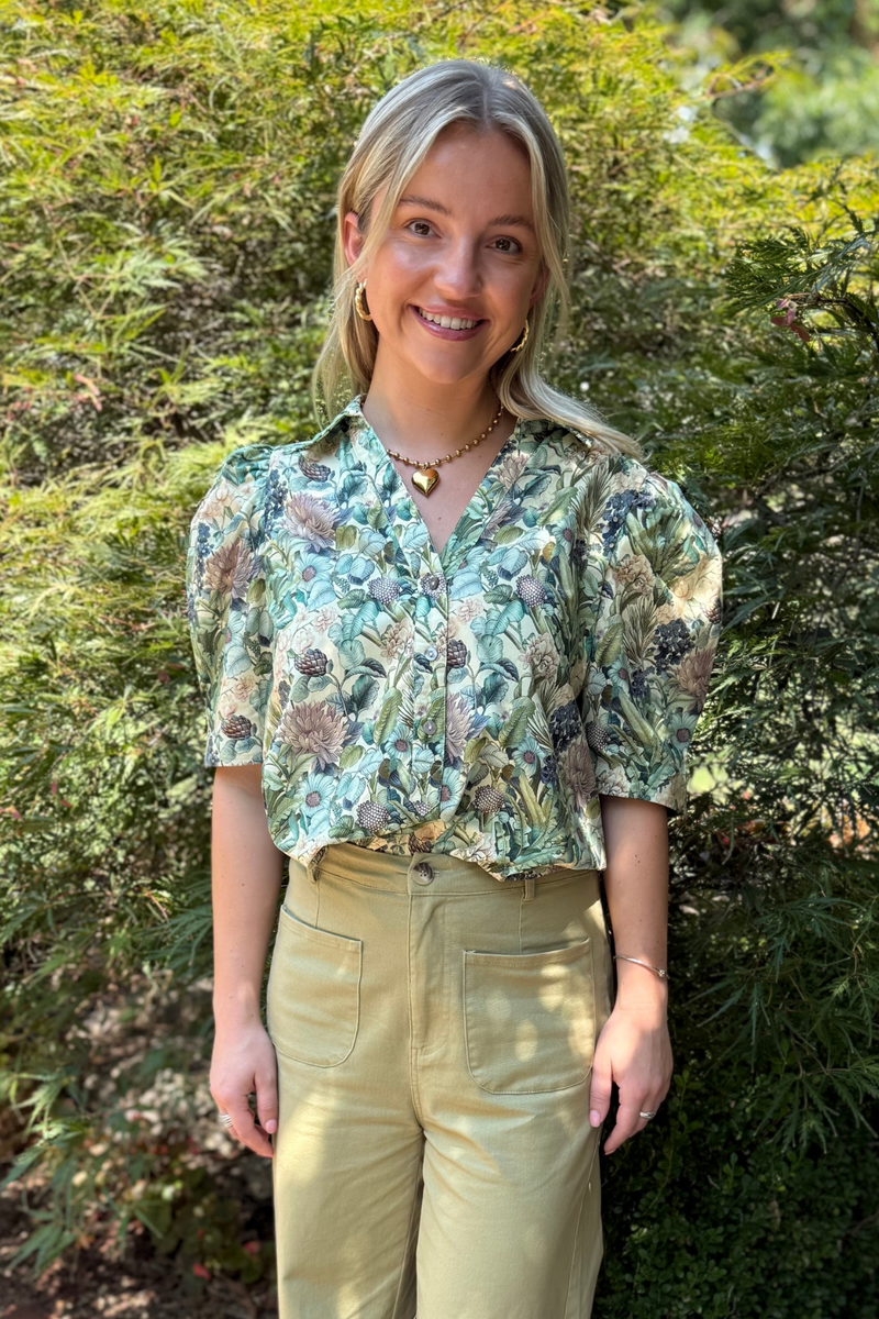 Model is wearing a 100% cotton short sleeve, sage botanical print top.