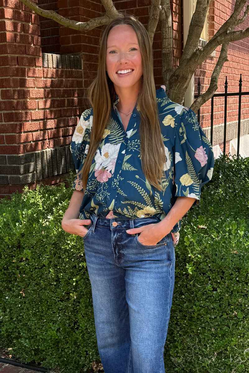 Model is wearing a teal botanical short sleeve button down shirt.