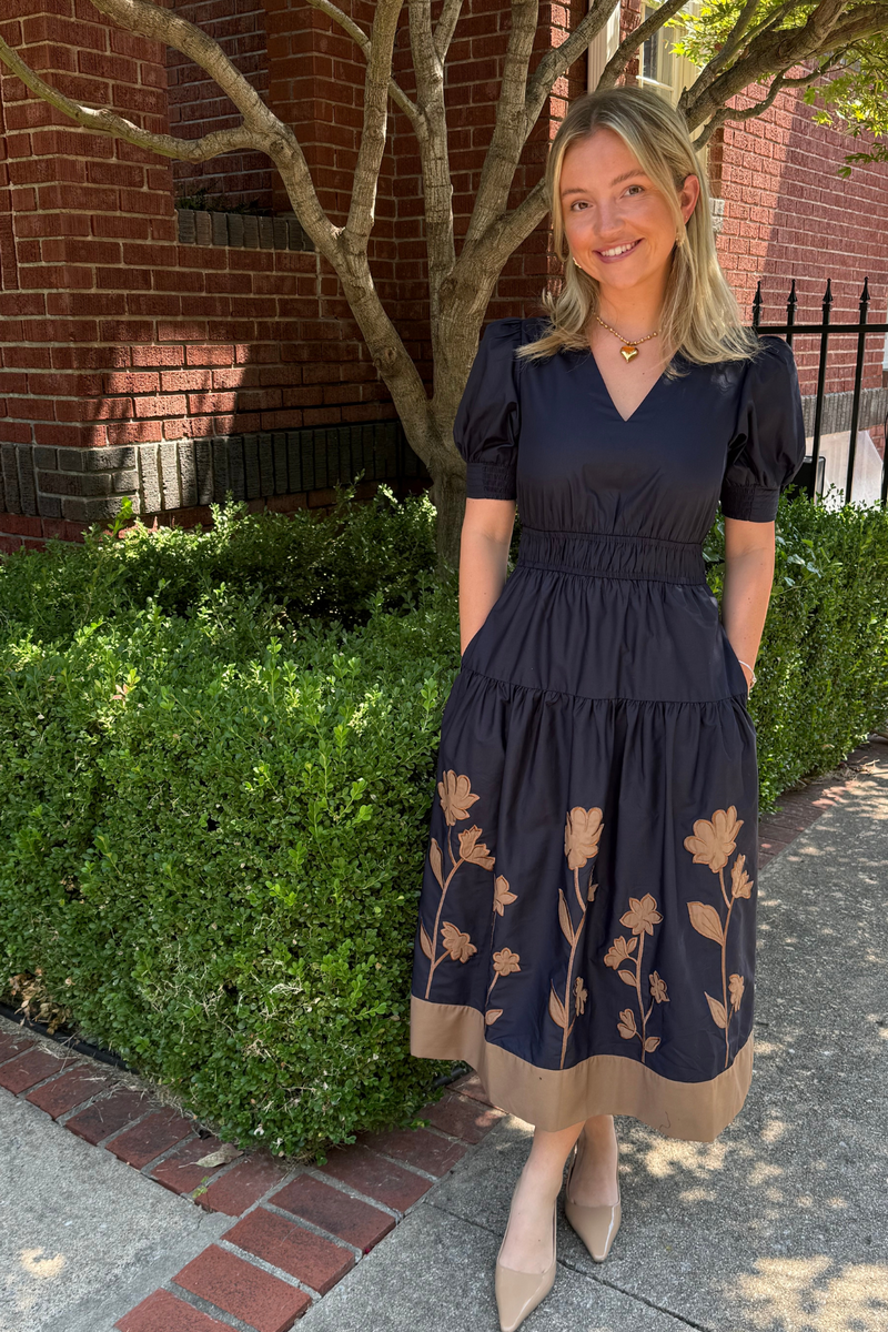Model is wearing a navy poplin midi dress with camel applique