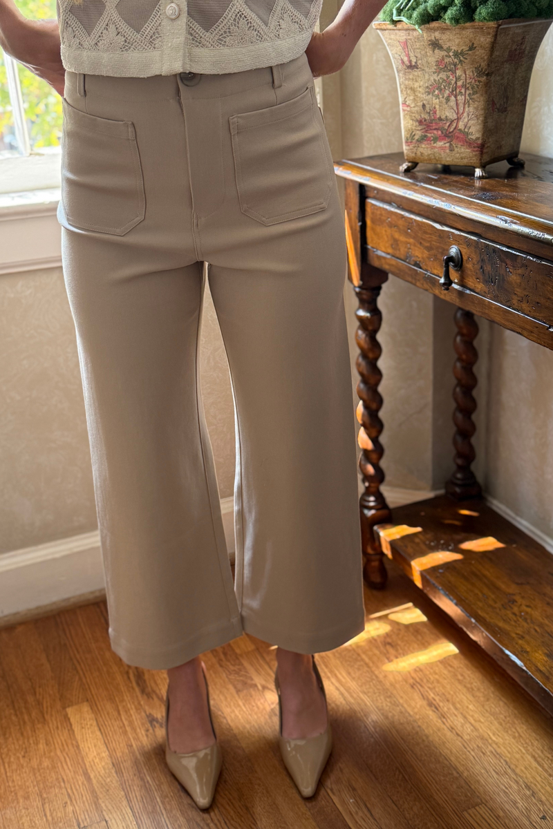 Model is wearing taupe cropped dress pants with front patch pockets