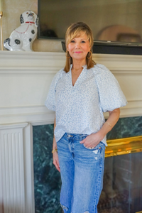 Model is wearing a pale blue, v-necki,  animal print top with puff sleeves.