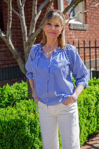 Model is wearing a blue and white striped top with self tie and 3/4" sleeves with ruffle detail at the wrist.