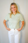 Model is wearing a light green and white striped t-shirt style knit top