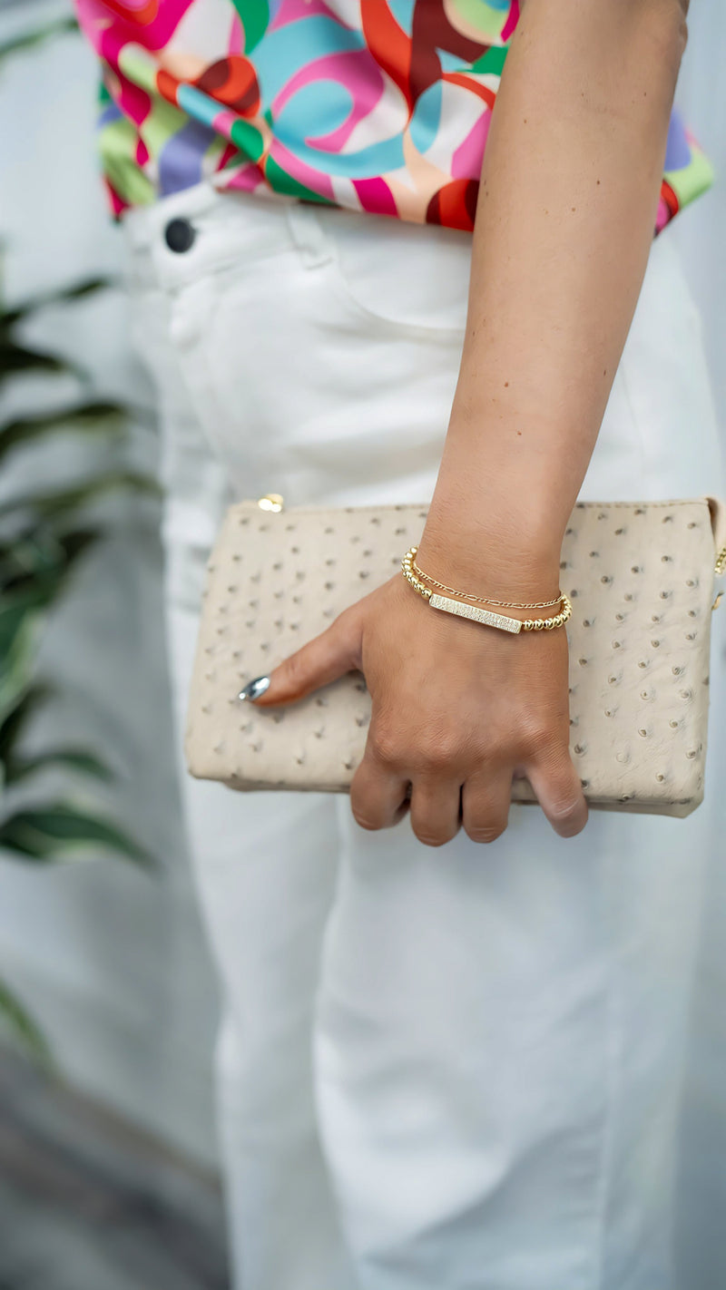 model is wearing a gold beaded bracelet with pave CZ bar detail