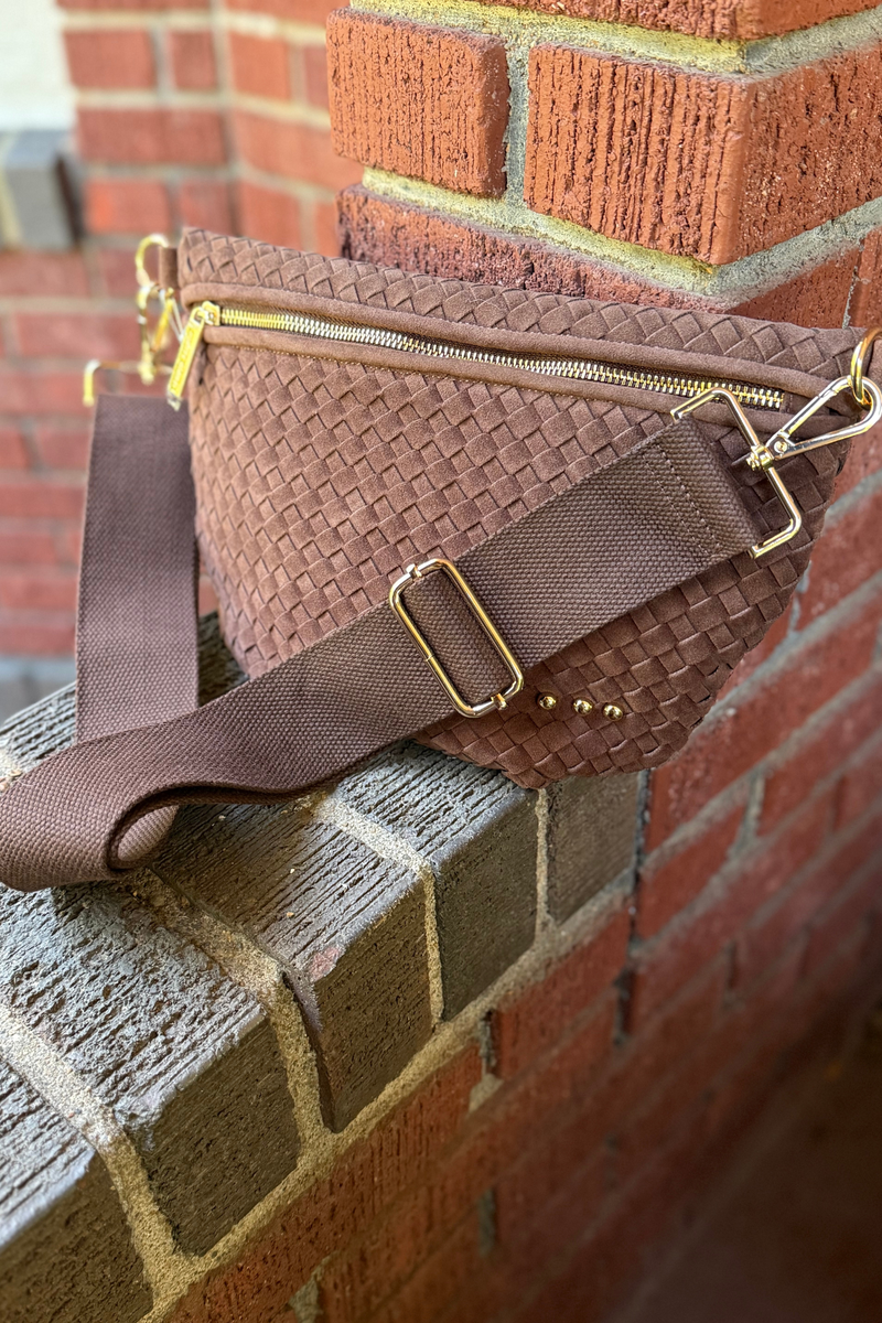 Photo is featuring a faux suede chocolate brown woven cross body bag with gold hardware
