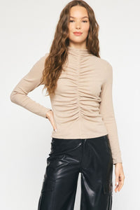 Model is wearing taupe long sleeve top with shirring detail