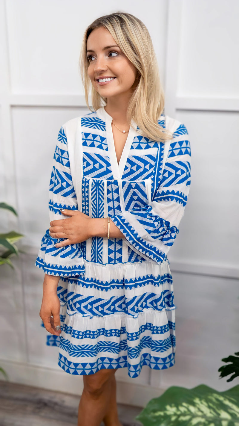 Model is wearing a THML blue and white embroidered dress. 