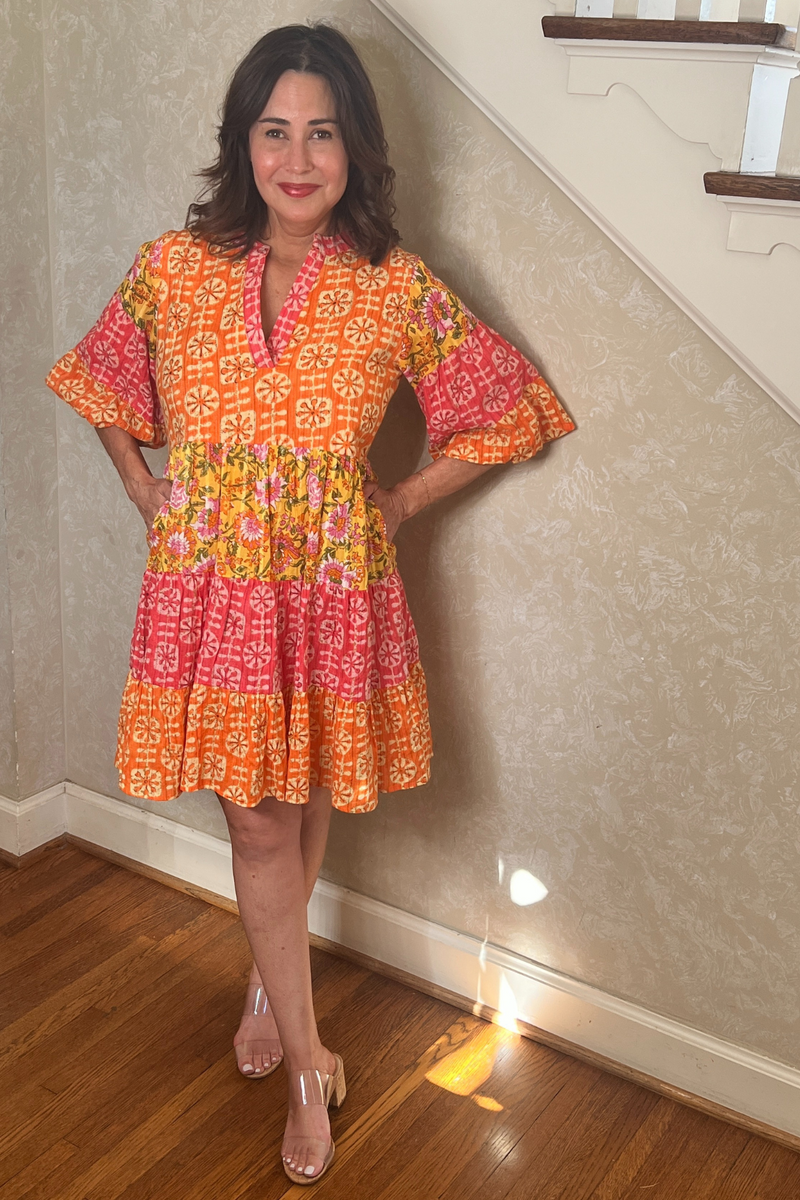 Model is wearing a THML Orange, Yellow, Pink and Green Dress with v-neck, puff sleeves and side pockets