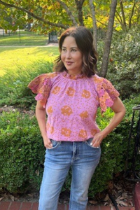 Model is wearing a pink and pumpkin block print top with yoyo sleeves