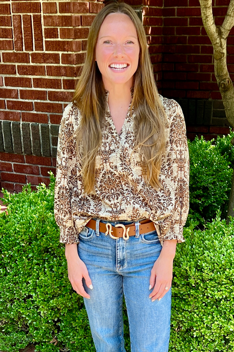 Model is wearing a chocolate, toffee and cream pattern top with 3/4 inch smocked sleeves and smocked v-neck design on the chest. This fall top has a lightweight fabrication making it comfortable for transitional seasons.