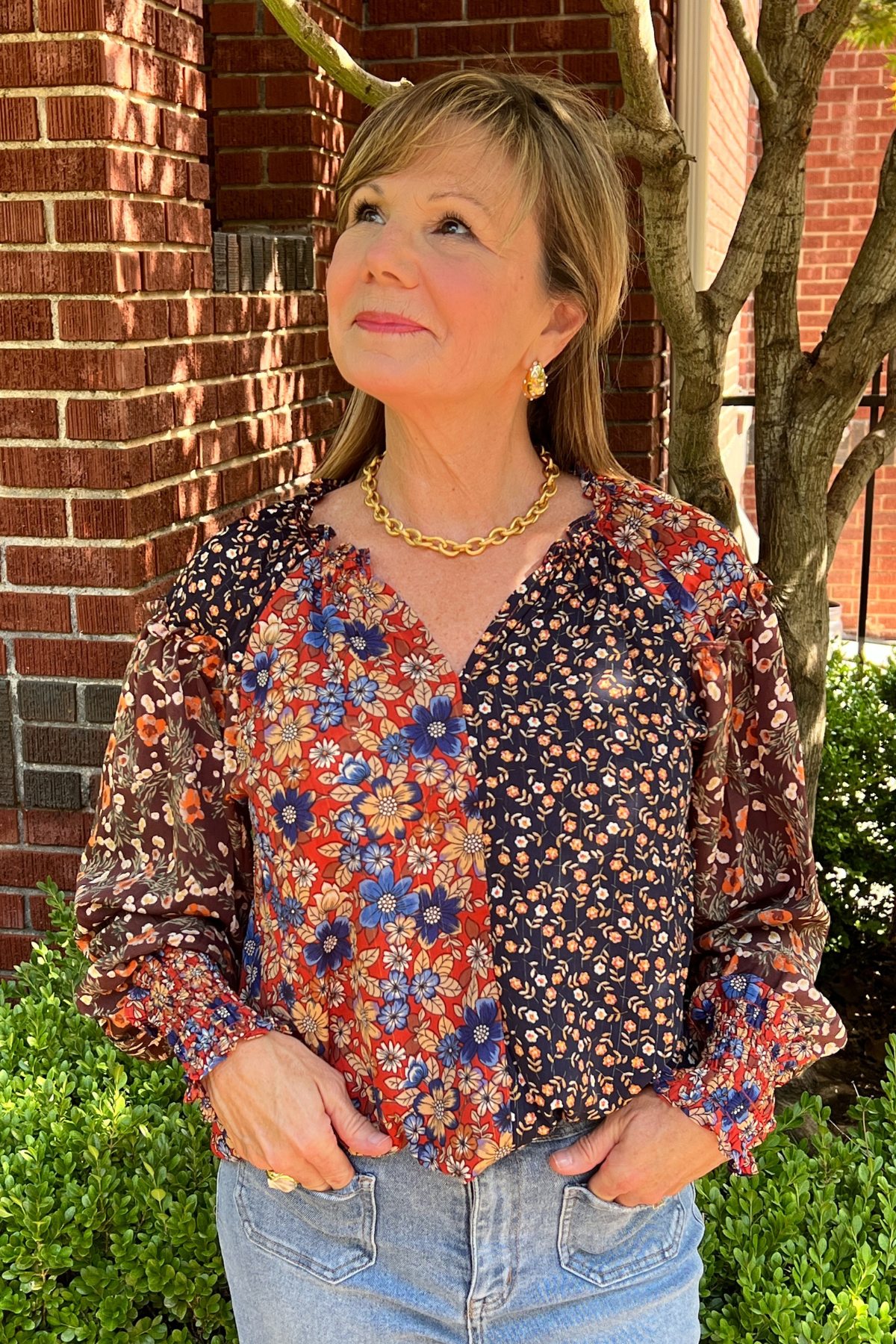 Model is wearing a long sleeved ditsy print top with ve neckline, ruched and ruffles at the wrists and peasant design.