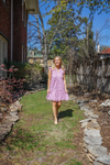 Model is wearing a lavender eyelet babydoll dress with ruffle cap sleeves