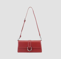 Red crossbody vegan leather  bag with adjustable strap, foldover flap closure and decorative silver buckle detail.