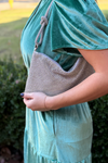 Model is carrying a silver rhinestone shoulder bag with knotted straps and a hobo design.